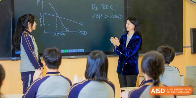 A Tianfu school The Integrated and Innovative Curriculum teacher writing on a blackboard with a student in the foreground.