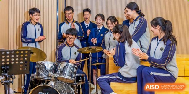 Students from Tianfu school The Integrated and Innovative Curriculum playing a drum set in a music room.