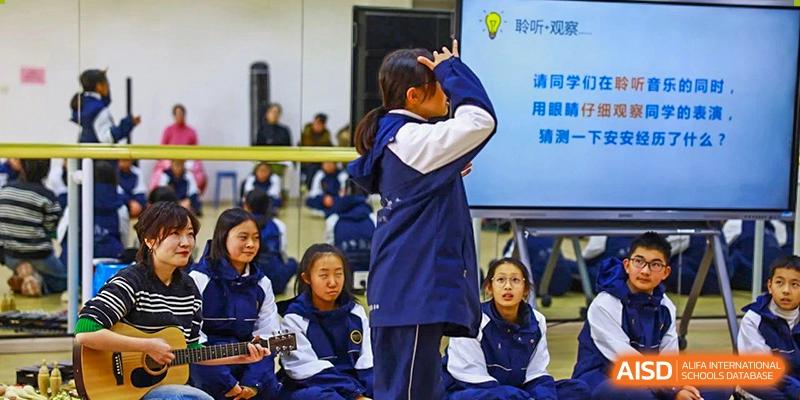 A Tianfu school The Integrated and Innovative Curriculum student standing and stretching in a crowded room with other students.