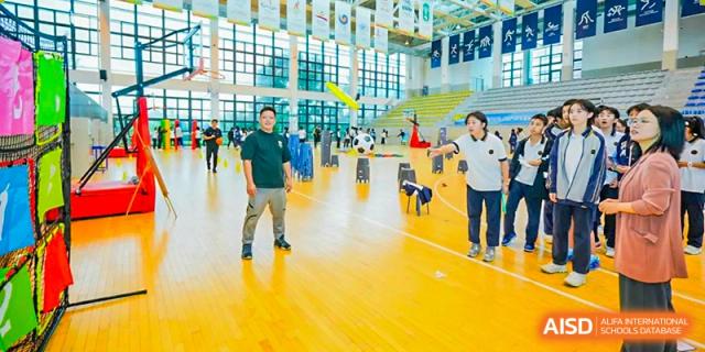 Students and teachers from Tianfu school The Integrated and Innovative Curriculum playing with a robot in an indoor gymnasium.