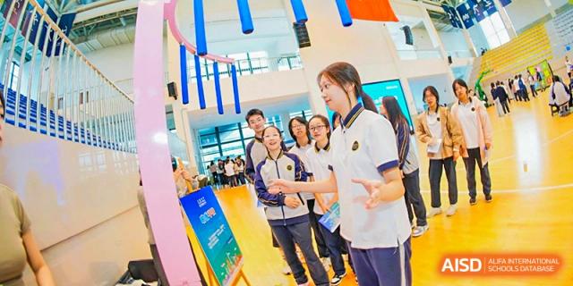 A group of Tianfu school The Integrated and Innovative Curriculum students smiling while gathered around a display board.