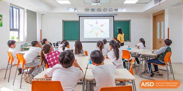 Students from Times College sitting in a classroom, watching a presentation on a screen at the front.
