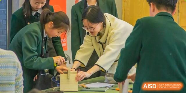 A student from Times College and a teacher working together on a project in a classroom.