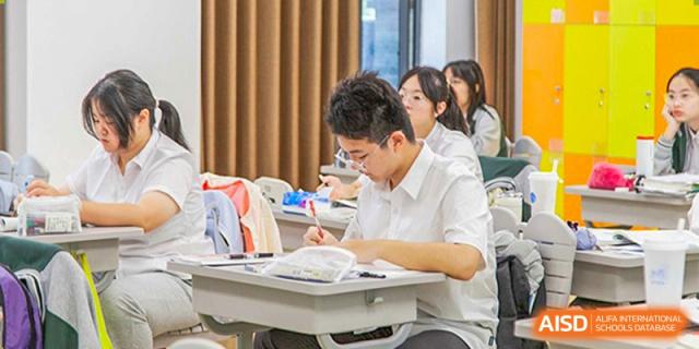 A student from Times College focused on their work at their desk during a class.