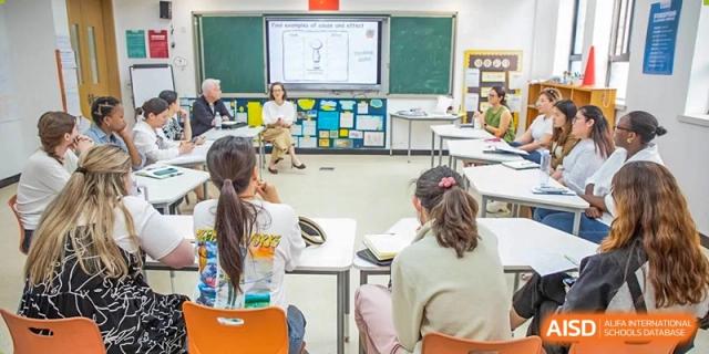 Students from Times College working together in a classroom.Young students from Times College reaching for food at a buffet table.