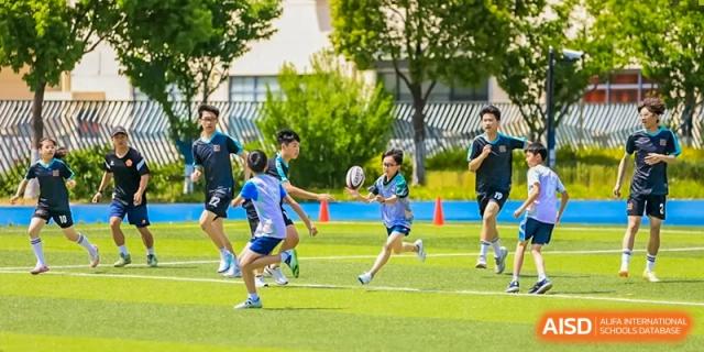 Students from Times College playing rugby on a green field during a sports event.