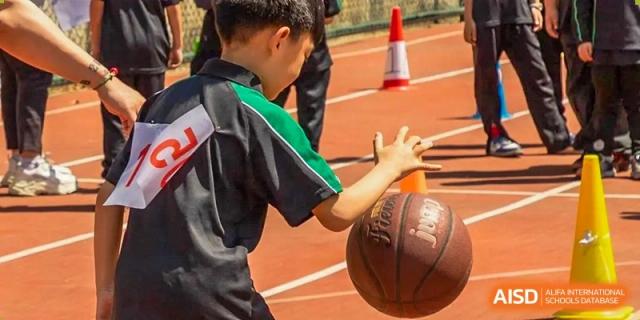 A student from Times College dribbling a basketball during a sports training session on a track.