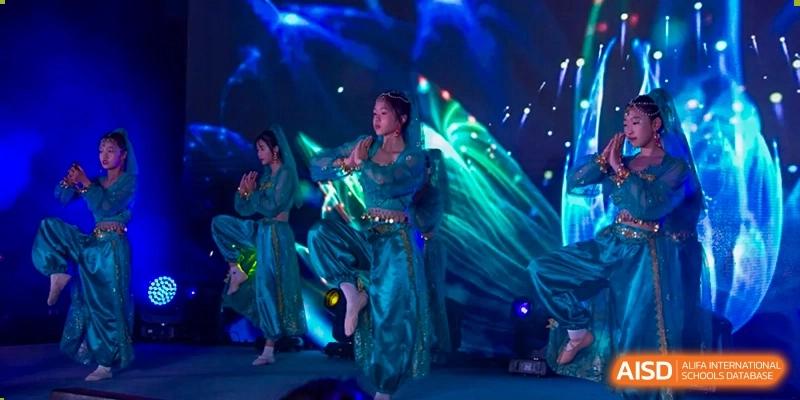 Students from Times College performing a dance on stage in vibrant costumes.