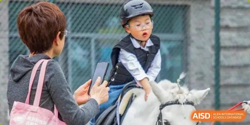 A young student from Times College wearing a helmet and vest while riding a horse.