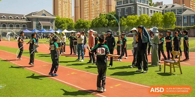 Students from Times College participating in a sports event, with one student standing on a running track.