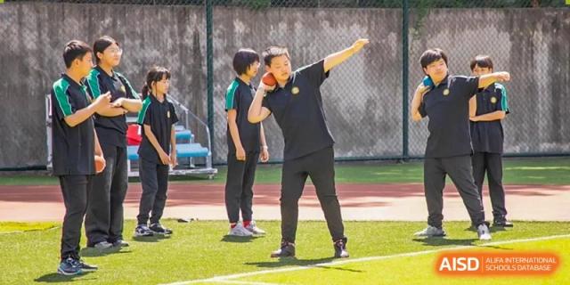 A teacher from Times College giving instructions to students during a physical education class.
