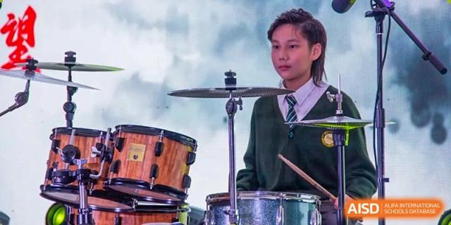A student from Times College playing the drums during a musical performance.