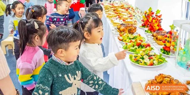 Young students from Times College reaching for food at a buffet table.
