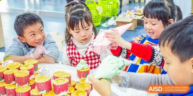 A young student from Times College decorating a cupcake with icing.