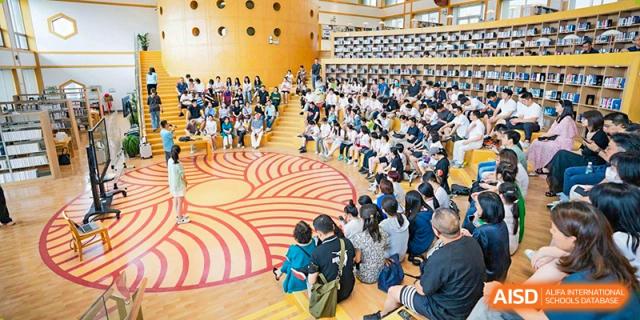 UWC Changshu China students and staff gathered in a circular lecture hall with a distinctive red and brown floor pattern.