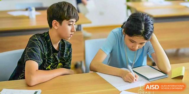 Two UWC Changshu China students writing and studying at a table in the library.