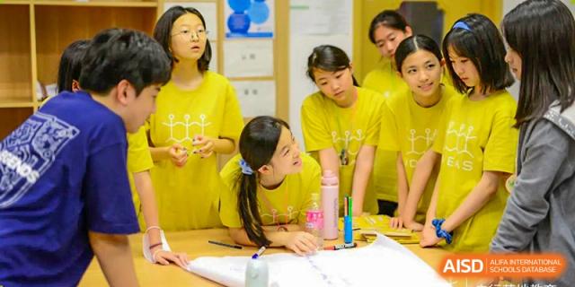 UWC Changshu China students working on a project with yellow paper and crayons.