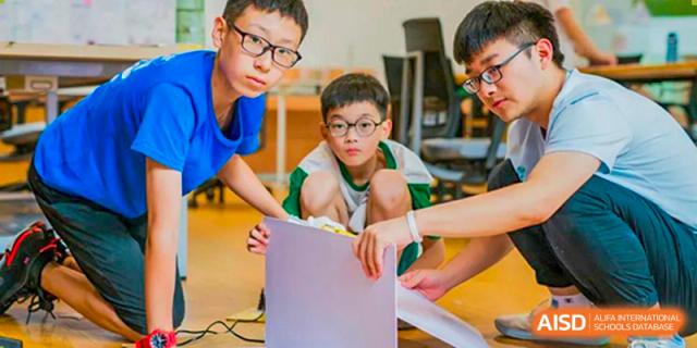 Two UWC Changshu China students collaborating on a project with a laptop.