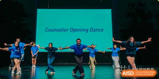 A group of students and a teacher are performing a dance on a stage with a banner that says "Counselor Opening Dance" at UWC Changshu China.