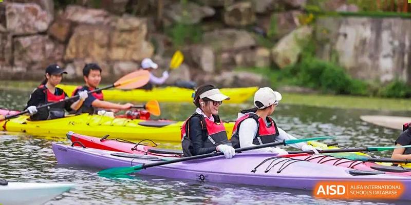 Two female students are paddling a yellow kayak on a lake at UWC Changshu China.