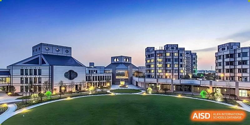 A modern school building with large windows and a green lawn in the foreground at UWC Changshu China.