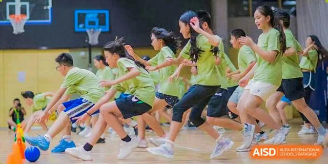 A group of students in green shirts runs together during a fun, outdoor game at UWC Changshu China.