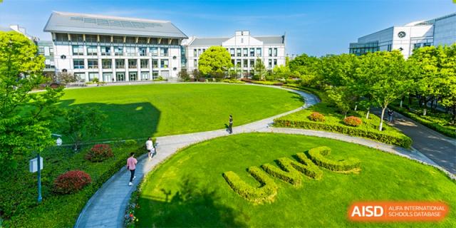 A large, well-maintained lawn with the letters "UWC" mowed into the grass in front of a white building at UWC Changshu China.