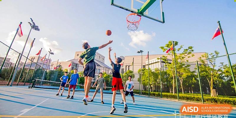 Male and female students play a game of basketball on an outdoor court at UWC Changshu China.