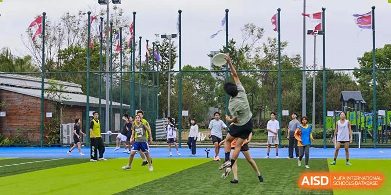 Students play ultimate frisbee on a grassy field at UWC Changshu China.