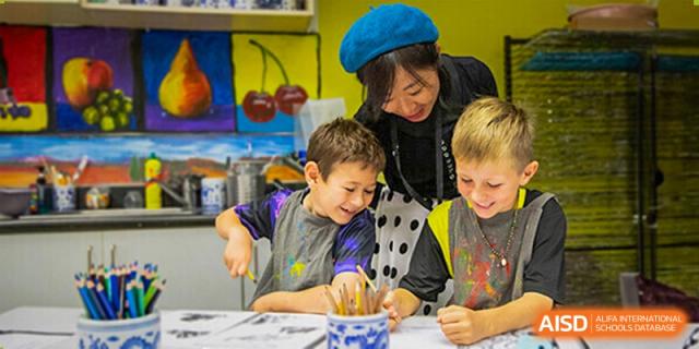 A Western Academy of Beijing teacher helps two young students with a hands-on project.