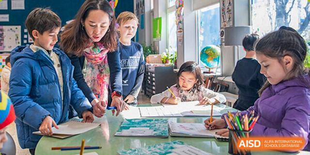 A group of Western Academy of Beijing students works on an art project with paint and paper.