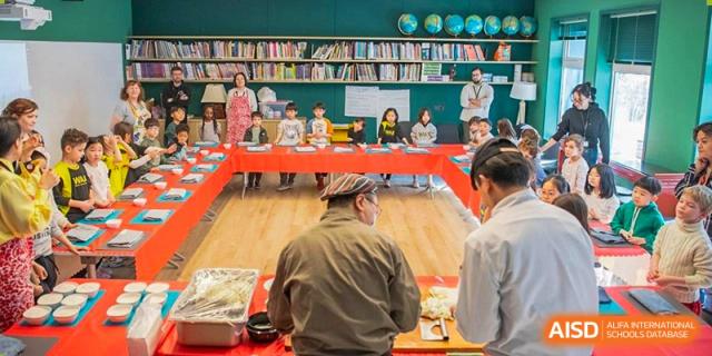 Western Academy of Beijing students sit at a long table with an instructor in a classroom or library.