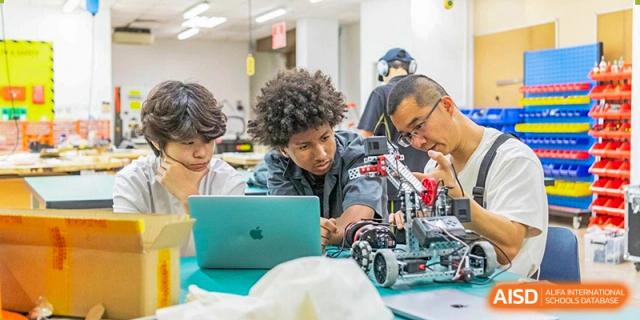 Western Academy of Beijing students work together on a robotics project with a laptop.