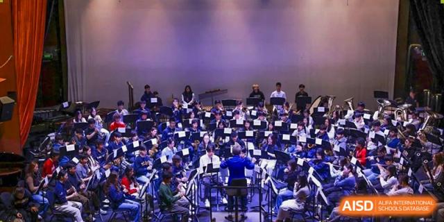 Western Academy of Beijing students sit in an auditorium, looking toward a stage.