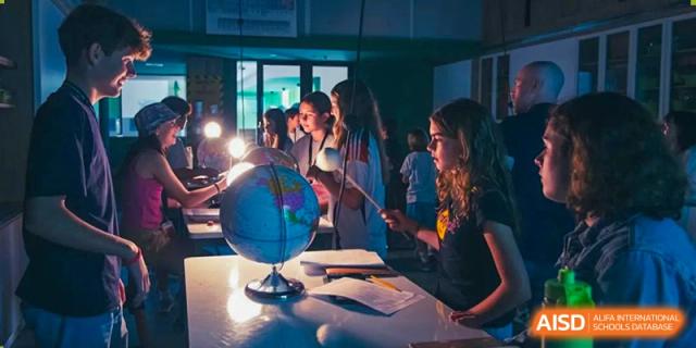 Western Academy of Beijing students sit on the floor, passing a globe around.