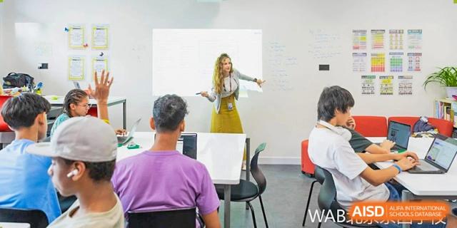 A Western Academy of Beijing teacher stands in front of a whiteboard, teaching students in a classroom.