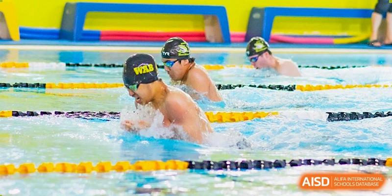 Two Western Academy of Beijing students swimming laps in an indoor pool.