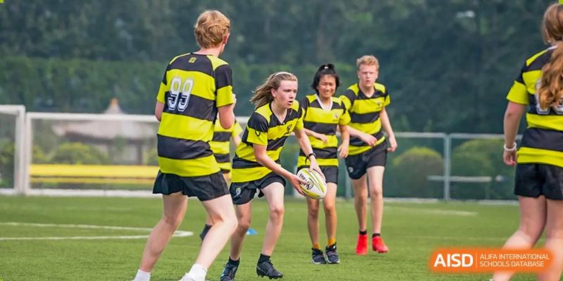 Western Academy of Beijing students playing rugby on a grass field.
