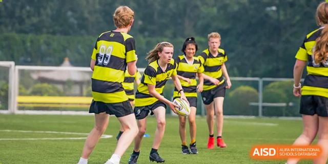 Western Academy of Beijing students playing rugby on a grass field.