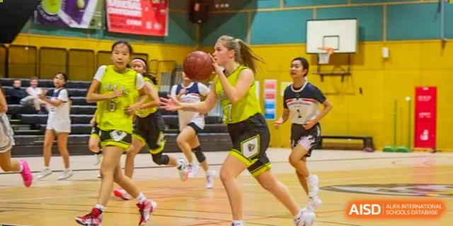 Western Academy of Beijing students playing basketball in a gymnasium.