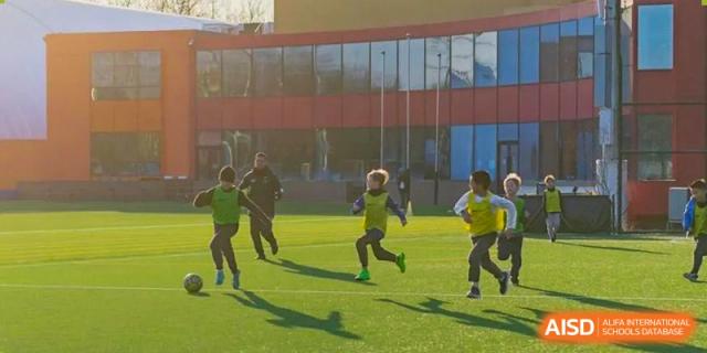 Western Academy of Beijing students playing soccer on a grass field.