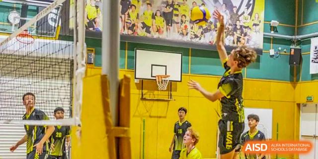 Western Academy of Beijing students playing volleyball in a gymnasium.