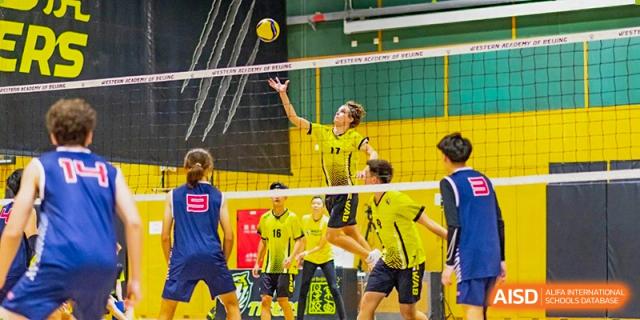 Western Academy of Beijing students playing volleyball in a gymnasium.