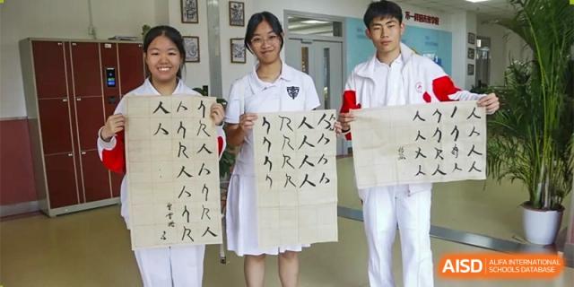 Several students hold up pieces of fabric with Chinese characters written on them, showing their work in a class at the Xishan School of The High School Affiliated to Renmin University of China.