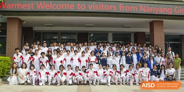 A large group of students in red and white uniforms is gathered for a photo in a school hallway at the Xishan School of The High School Affiliated to Renmin University of China.