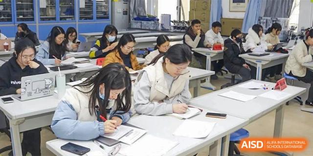 A group of students is studying and working on laptops in a library or study hall at the Xishan School of The High School Affiliated to Renmin University of China.