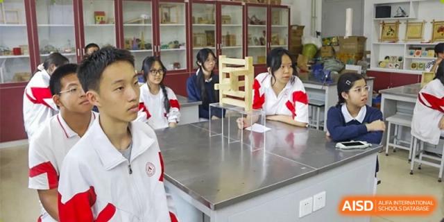 A male student in a white uniform is working on a science experiment at a lab table at the Xishan School of The High School Affiliated to Renmin University of China.