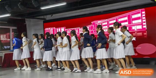 Students from Xishan School of The High School Affiliated to Renmin University of China perform a choreographed dance on a stage.