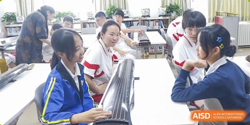 A close-up of students from Xishan School of The High School Affiliated to Renmin University of China, with one student playing a musical instrument while others watch.