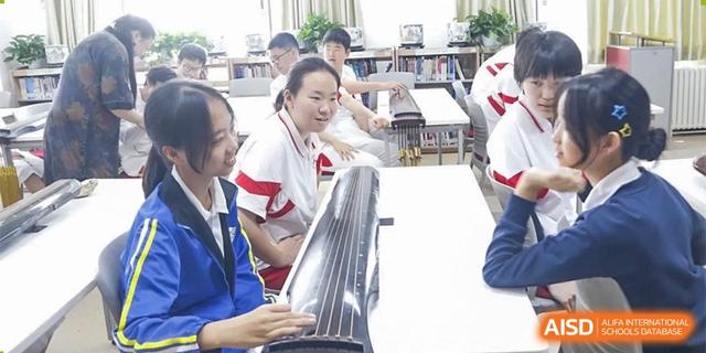 A close-up of students from Xishan School of The High School Affiliated to Renmin University of China, with one student playing a musical instrument while others watch.